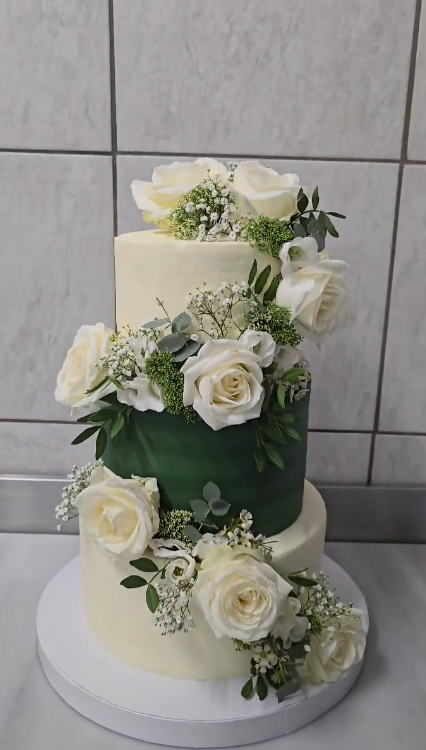 Tiered cake with white roses and a moss-green centre tier